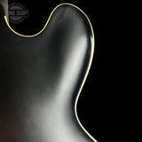 Close-up of a guitar's body with a visible brand logo in the corner.