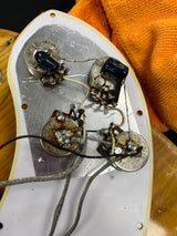 Close-up of an electronic device with wiring and components on a wooden surface.