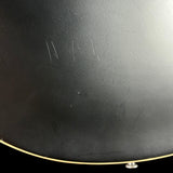 Close-up of a black guitar with visible wear and tear