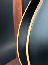 Close-up of a guitar's soundhole with a dark body and gold trim.