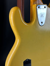 Close-up of a yellow electric guitar with a visible brand logo on the body.