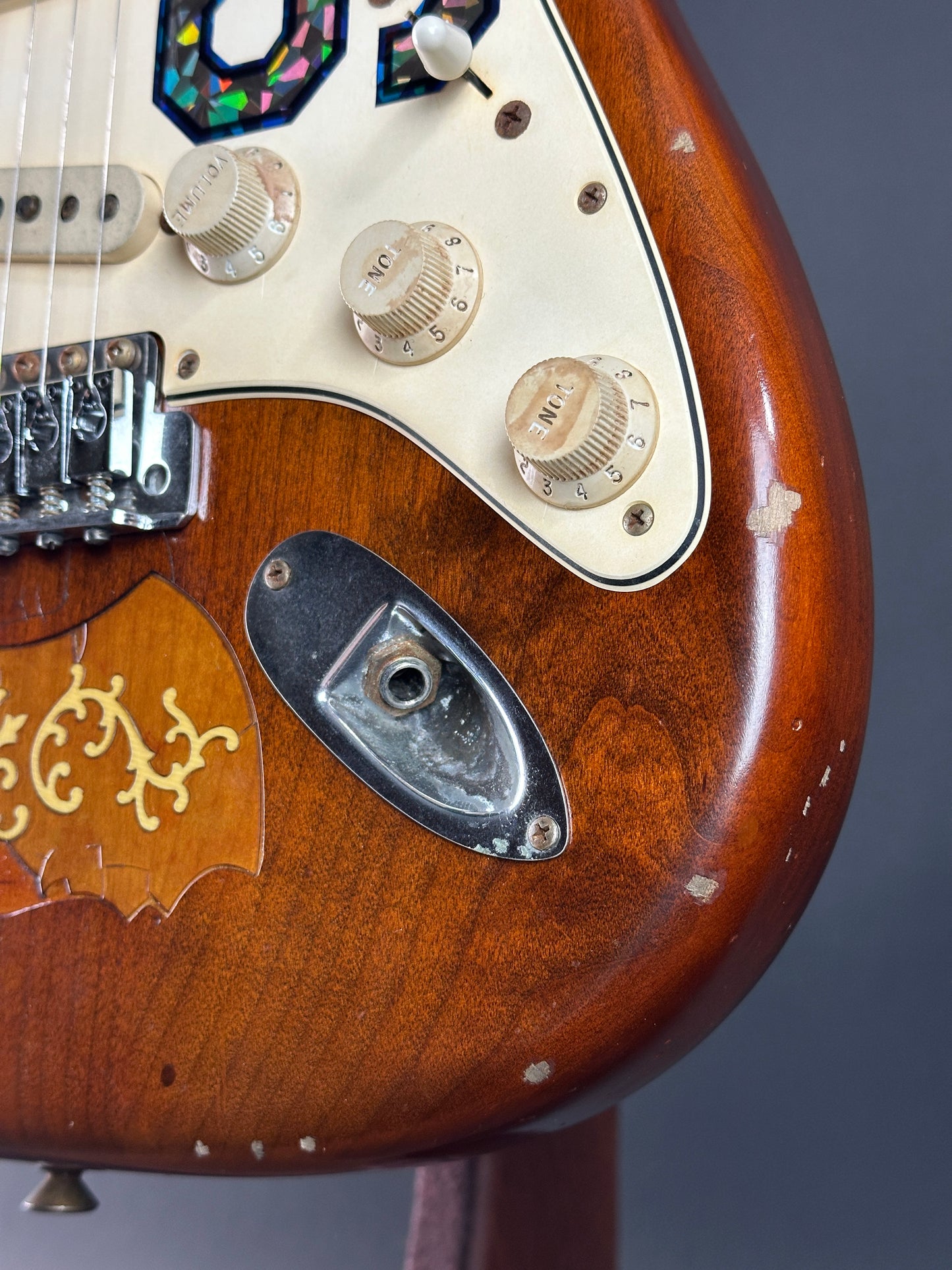 Close-up of a vintage electric guitar with wood finish and control knobs.