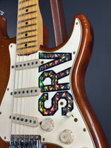 Close-up of a guitar with 'SRV' logo on a dark background