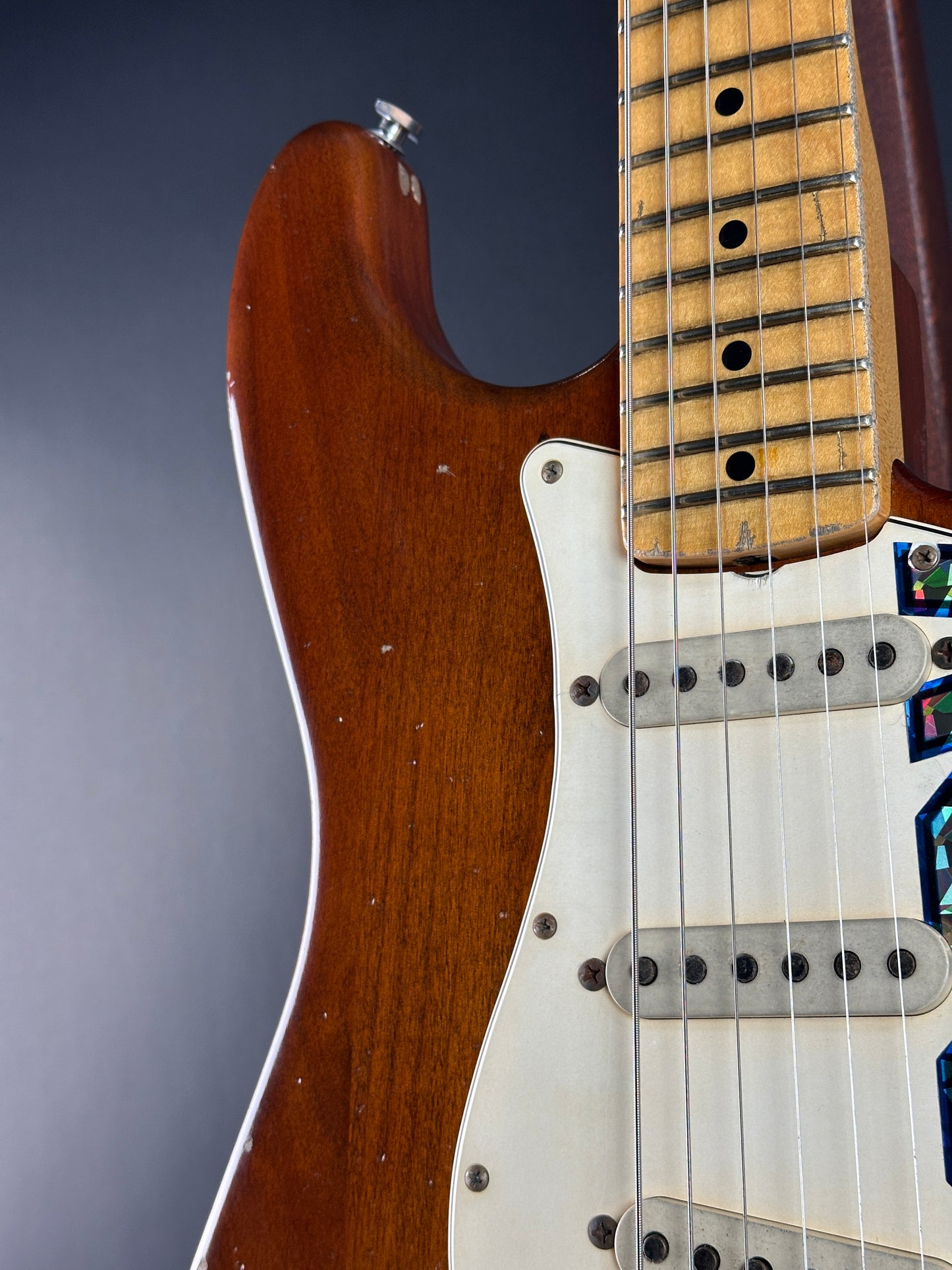 Close-up of a guitar's neck and body on a gray background