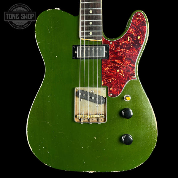 Green electric guitar with red pickguard on a black background