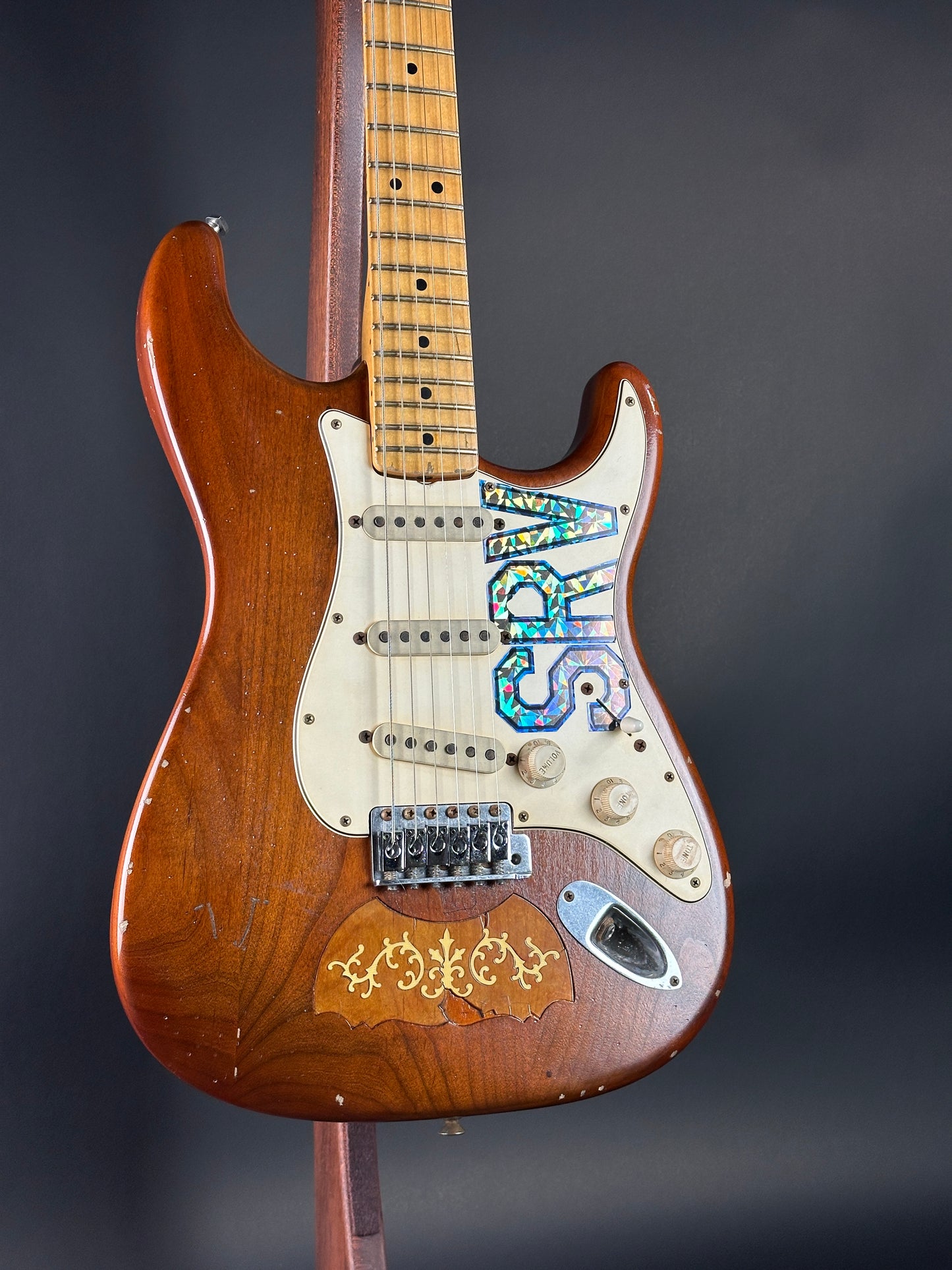 Wooden electric guitar with decorative elements on a dark background