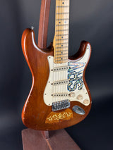 Wooden electric guitar with a visible brand logo on a dark background