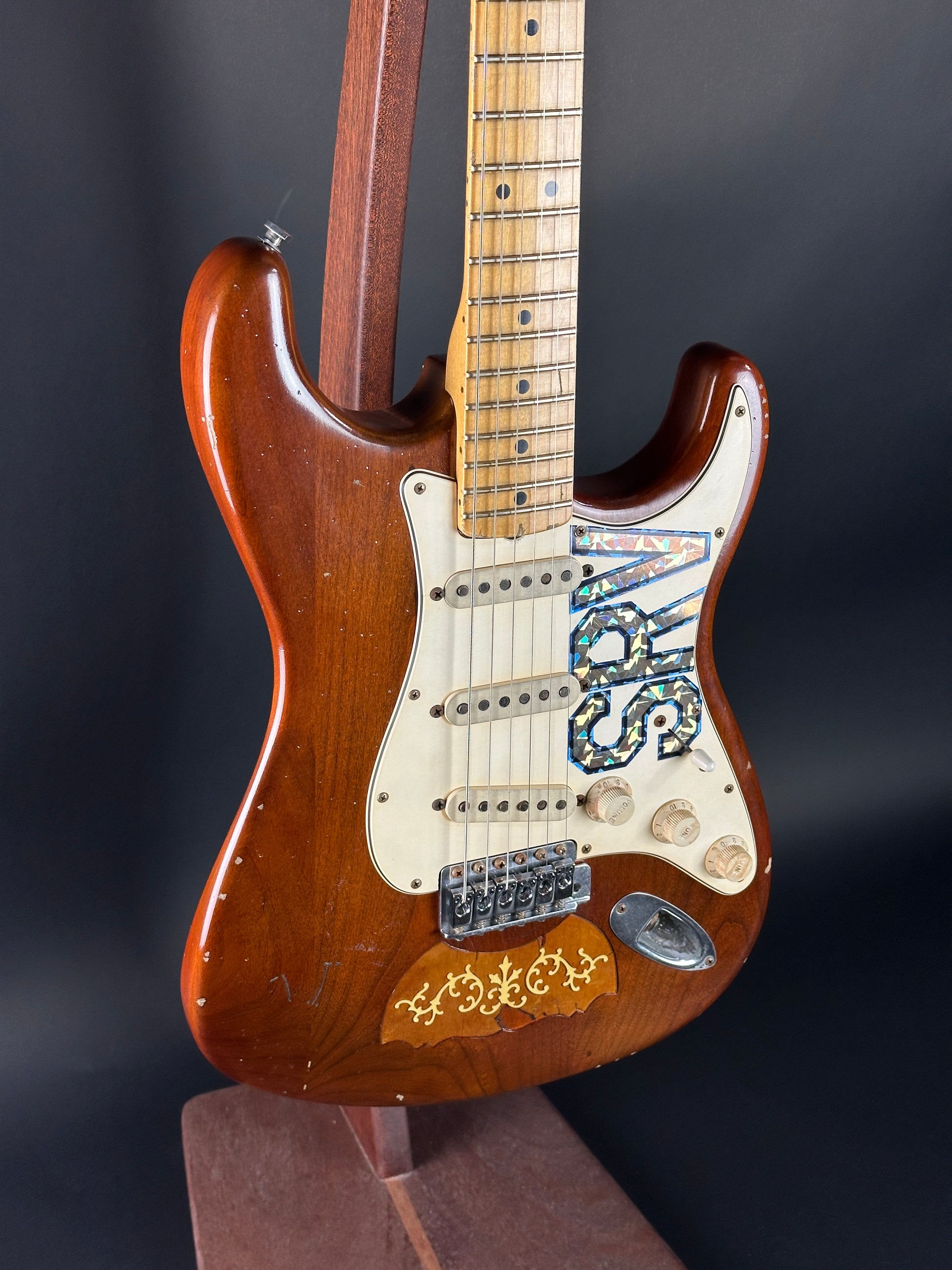 Wooden electric guitar with a visible brand logo on a dark background