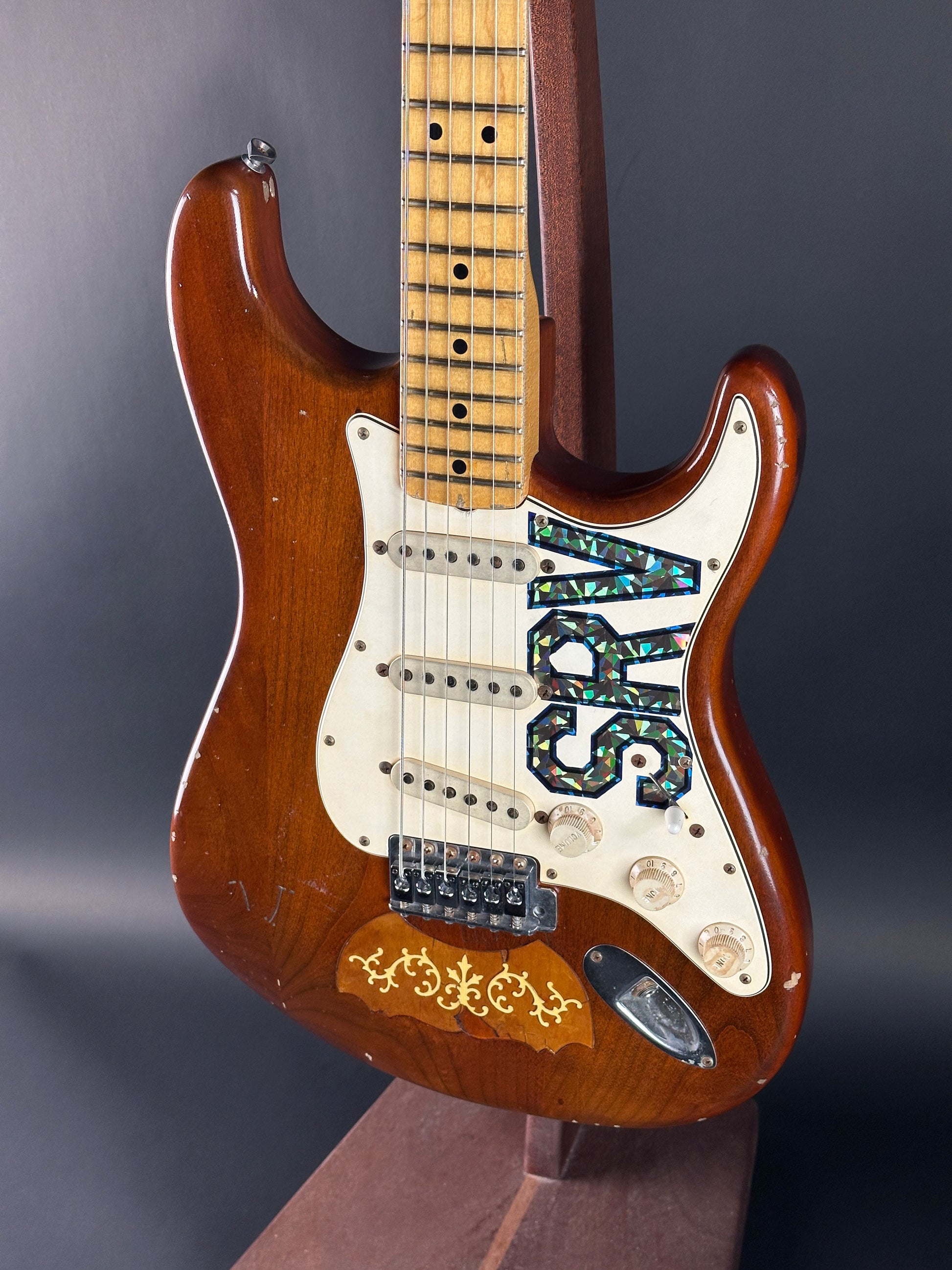 Close-up of a electric guitar with 'SRV' branding on a dark background