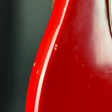 Close-up of a glossy red guitar body edge with a white binding line and a small portion of a light-colored headstock visible at the top right.