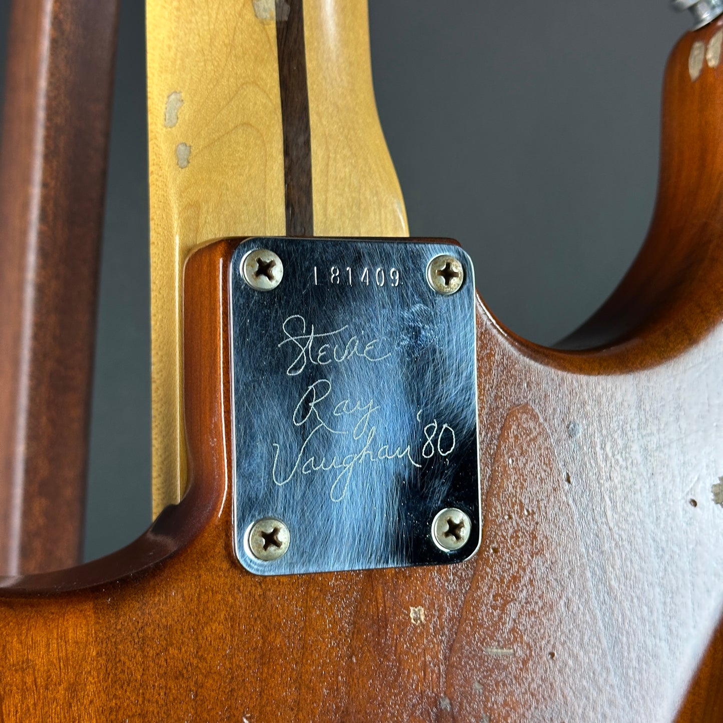 Guitar neck with a branded label on a dark background
