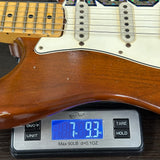 Wooden electric guitar on a digital scale displaying weight.