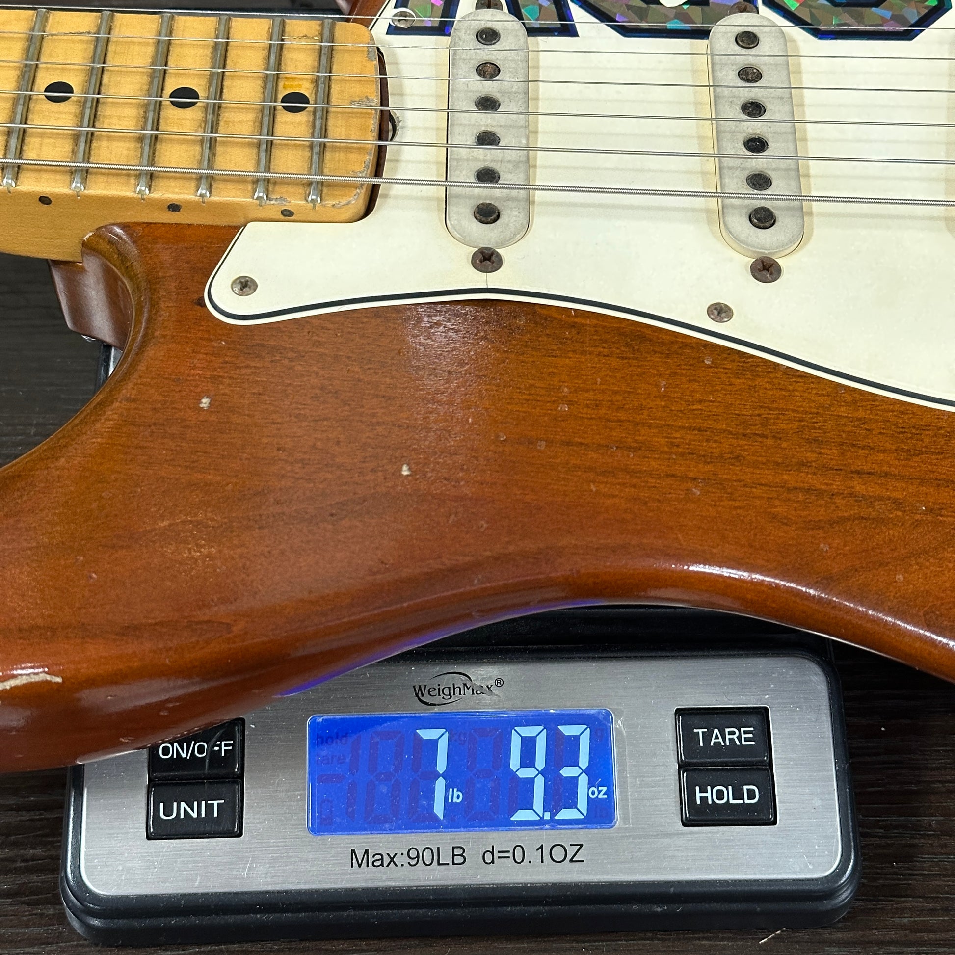 Wooden electric guitar on a digital scale displaying weight.