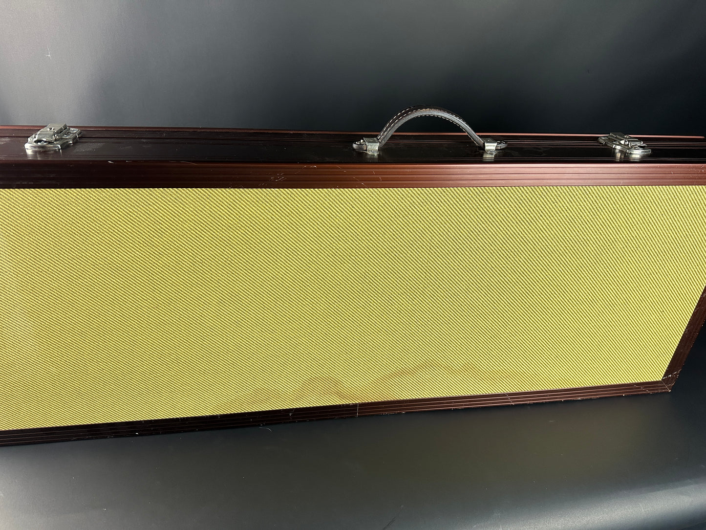 Guitar case with a textured yellow front panel on a dark background