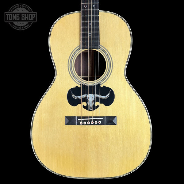 Acoustic guitar with a bull logo on a black background, featuring the Tone Shop logo.