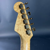 Close-up of a guitar headstock with tuning pegs on a blue background