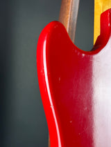 Close-up of the glossy red body of an electric guitar against a dark gray background.