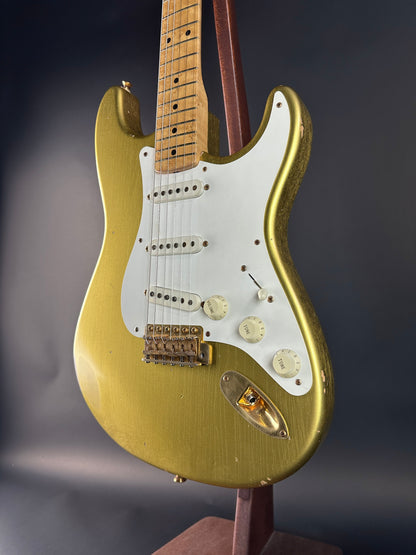 Gold electric guitar on a stand against a dark background