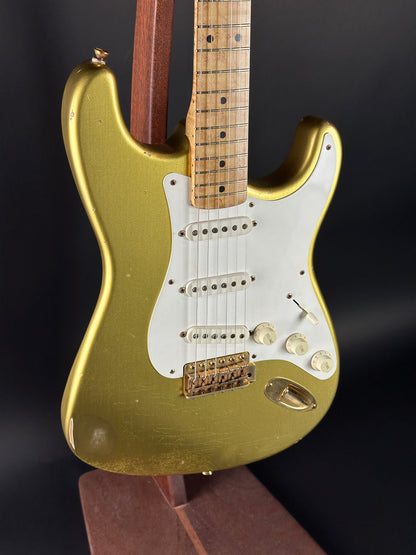 Gold electric guitar on a stand against a dark background