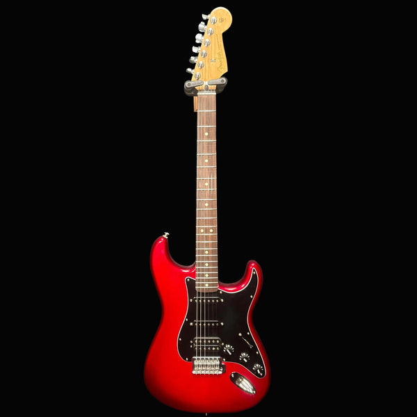 Red electric guitar with a black pickguard on a dark background