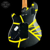The back of a black electric guitar with a distinctive yellow tape pattern wrapping across its body, shown against a solid black background.