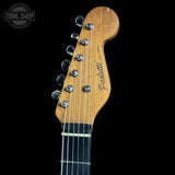 Close-up of a guitar headstock with 'Pardini Guitars' branding on a black background.