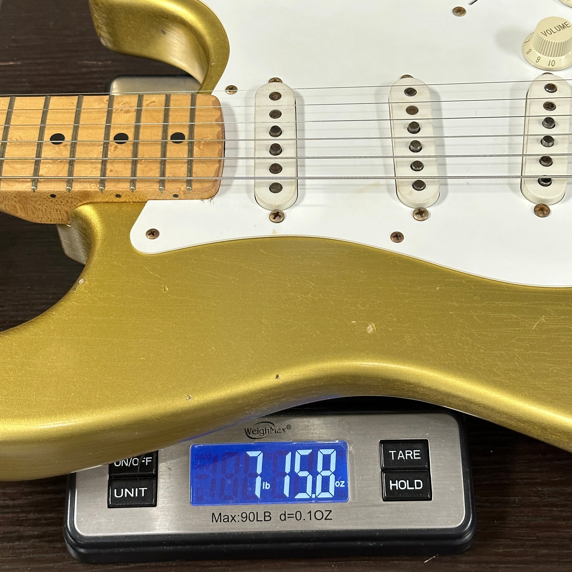 Gold electric guitar on a digital scale displaying weight
