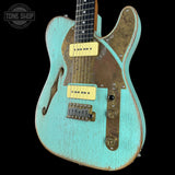 Vintage turquoise electric guitar with a worn finish on a black background, featuring 'Tone Shop' branding.