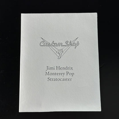 White guitar case with 'Custom Shop' and 'Jimi Hendrix Monterey Pop Stratocaster' text on a black background