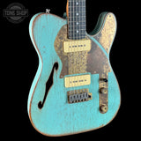Vintage-style electric guitar with turquoise finish and worn metal parts on a black background.