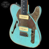 Distressed turquoise electric guitar with brown accents on a black background, featuring 'Tone Shop' branding.