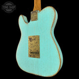 Turquoise electric guitar with a worn finish on a black background, featuring the Tone Shop logo.