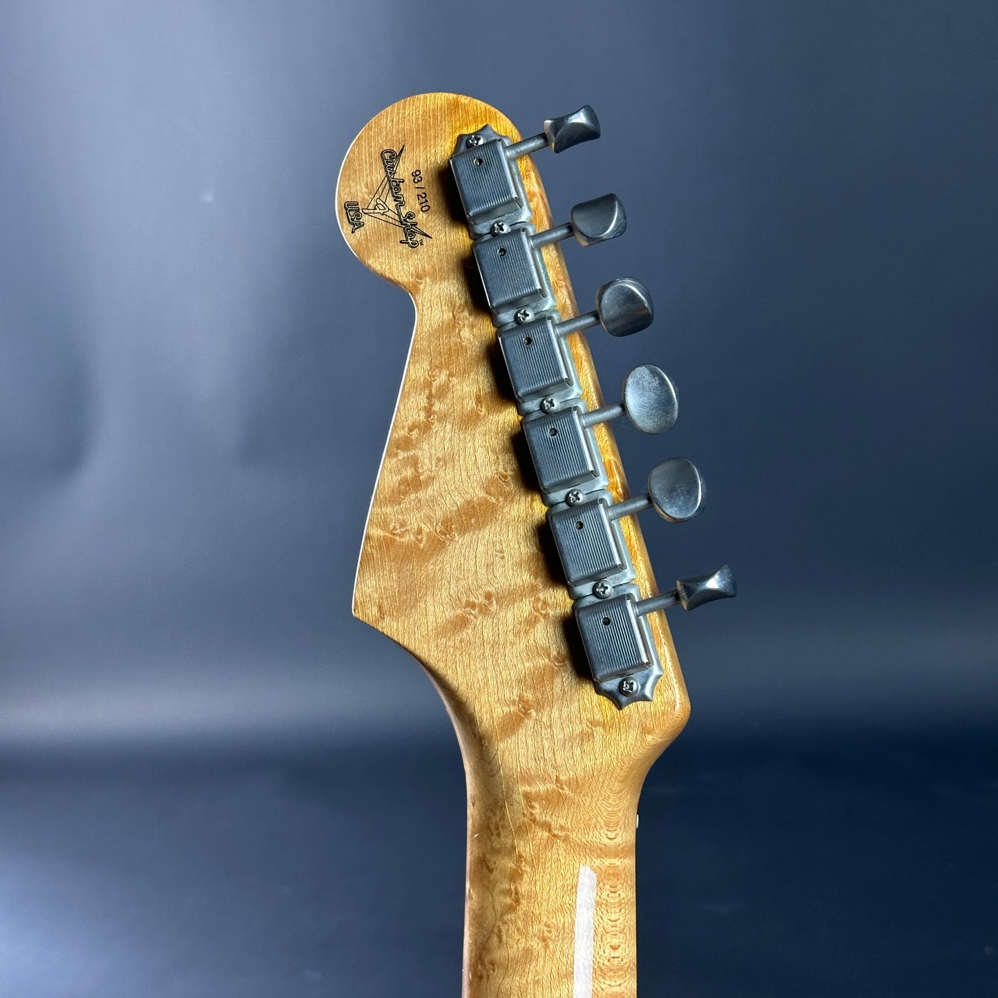 Guitar headstock with tuning pegs on a dark blue background