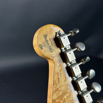 Close-up of a guitar headstock with tuning pegs on a dark background