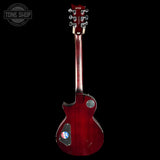 A red electric guitar shown from the back against a solid black background, featuring a glossy cherry red finish, dual pickups, and a Tune Shop logo sticker on the lower back.