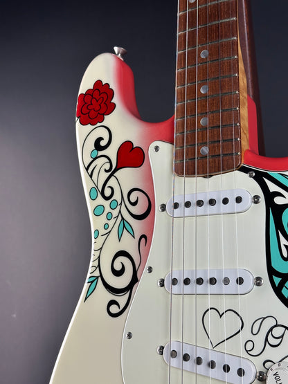 Close-up of a guitar with decorative designs on the body against a dark background