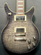 Close-up of a guitar with a focus on the neck, body, and hardware against a dark background.