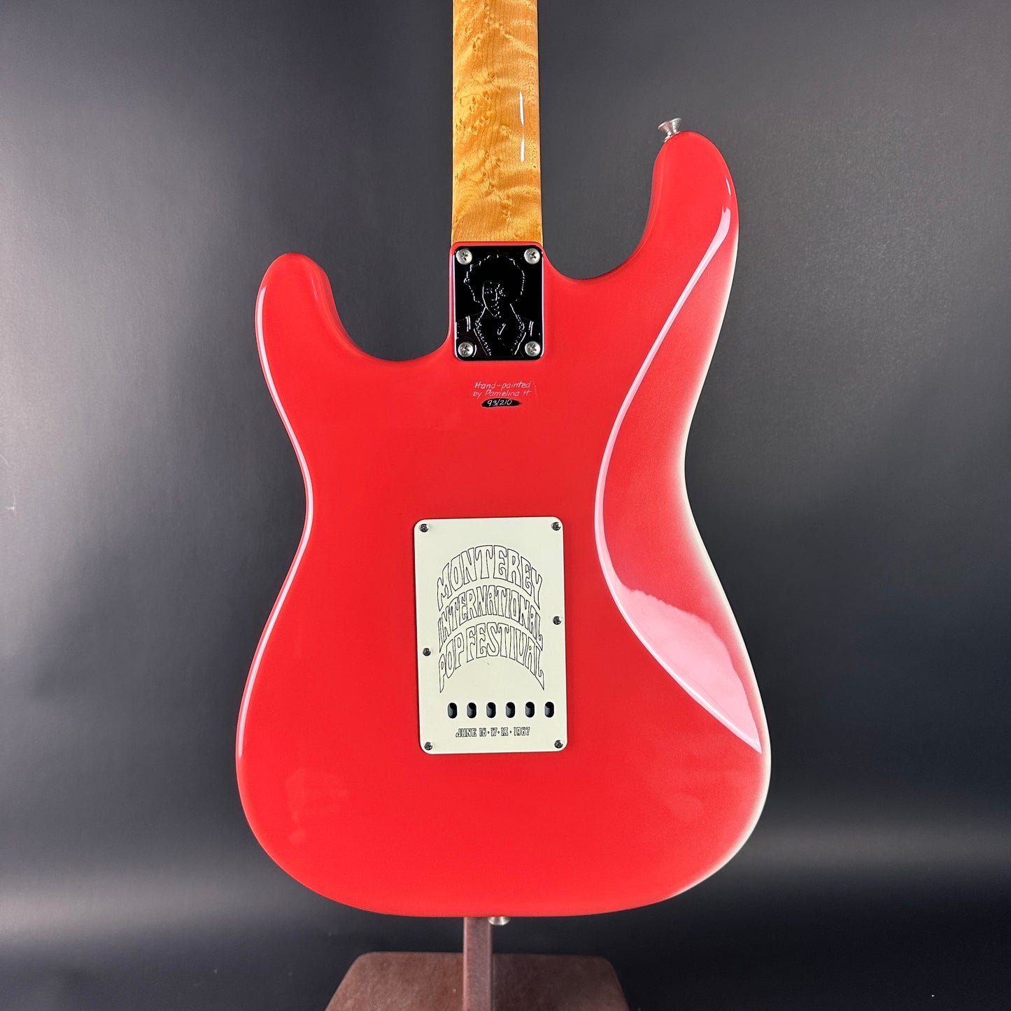 Red electric guitar on a stand against a dark background