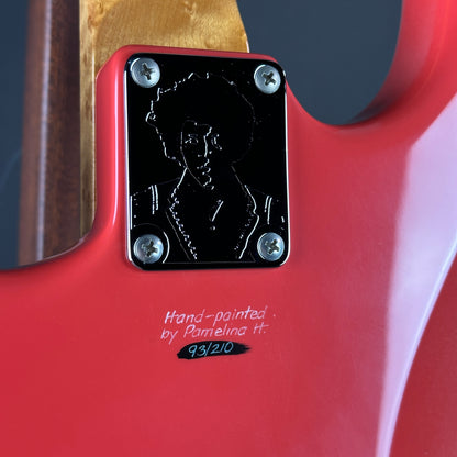 Close-up of a red guitar with a black label and hand-painted signature.