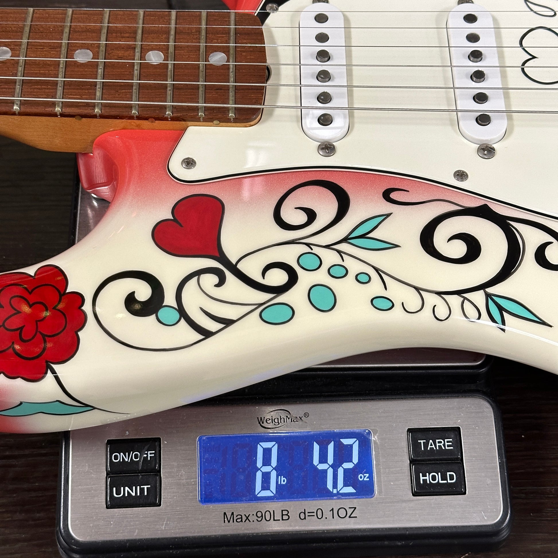Guitar with decorative design on a digital scale showing weight