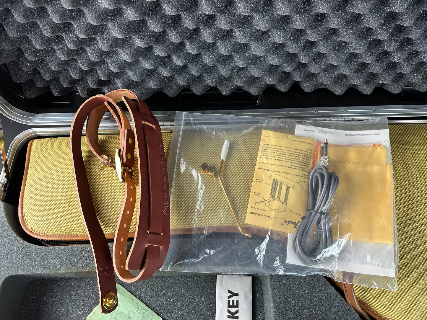 Leather strap, cable, and manual inside a case with visible brand name.