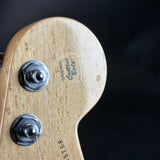Close-up of a wooden guitar headstock with 'Fender' branding on a black background
