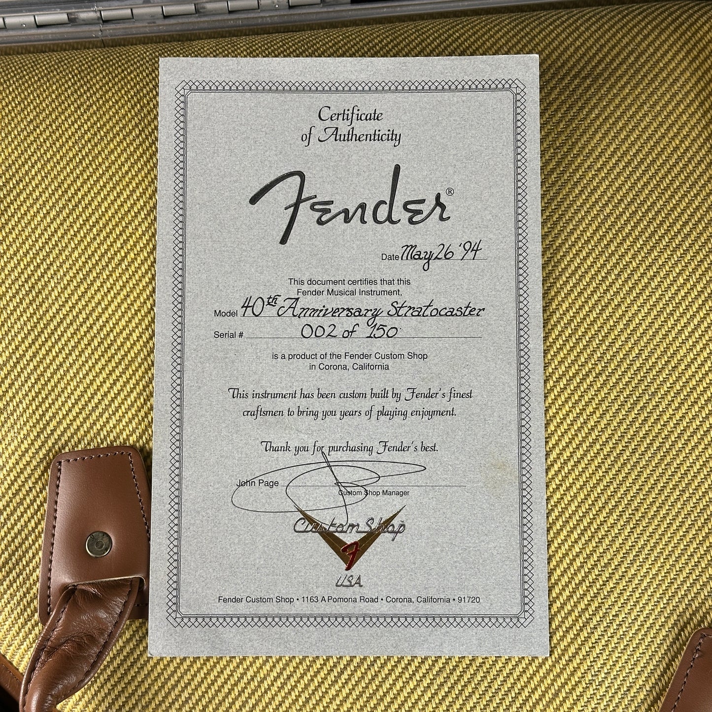 Fender certificate of authenticity on a guitar case with a guitar strap.
