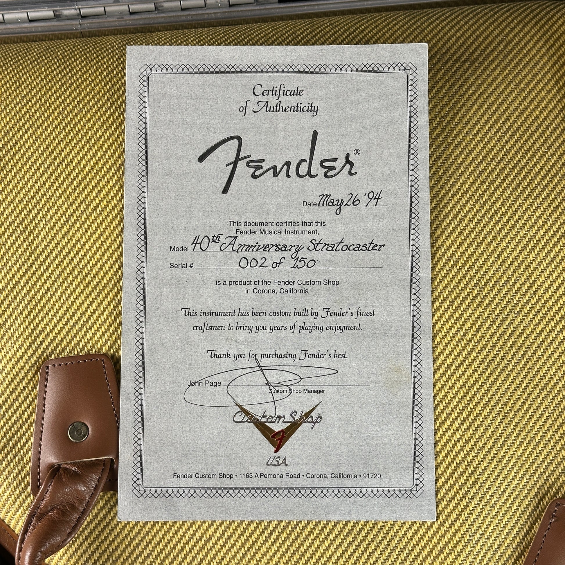 Fender certificate of authenticity on a guitar case with a guitar strap.