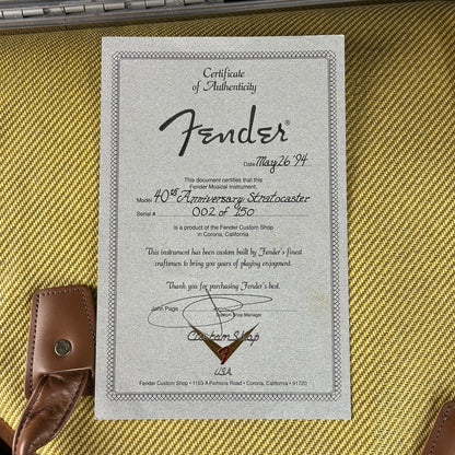 Fender certificate of authenticity on a guitar case with a guitar strap.