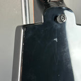 Close-up of a glossy black guitar body with a visible screw and some surface scratches, against a neutral gray background.