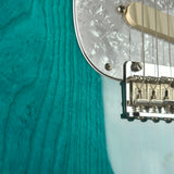 Close-up of a teal electric guitar with a focus on the neck and fretboard.