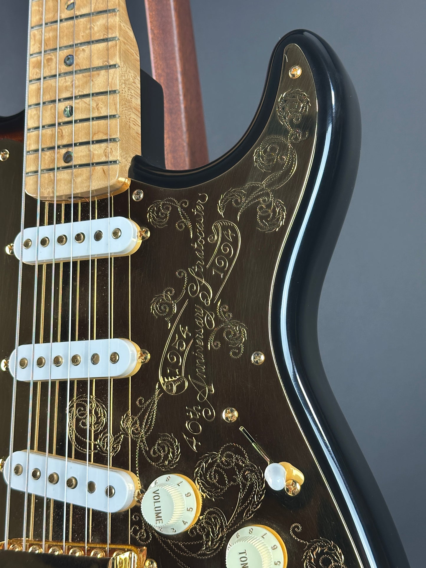 Close-up of a guitar's neck and headstock with intricate designs and branding.