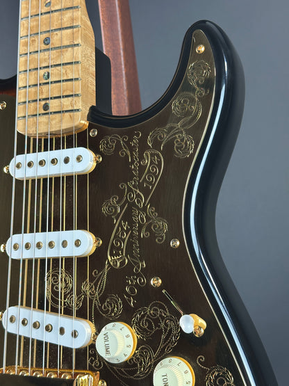 Close-up of a guitar's neck and headstock with intricate designs and branding.