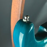Close-up of a blue guitar neck with a wooden headstock against a dark background
